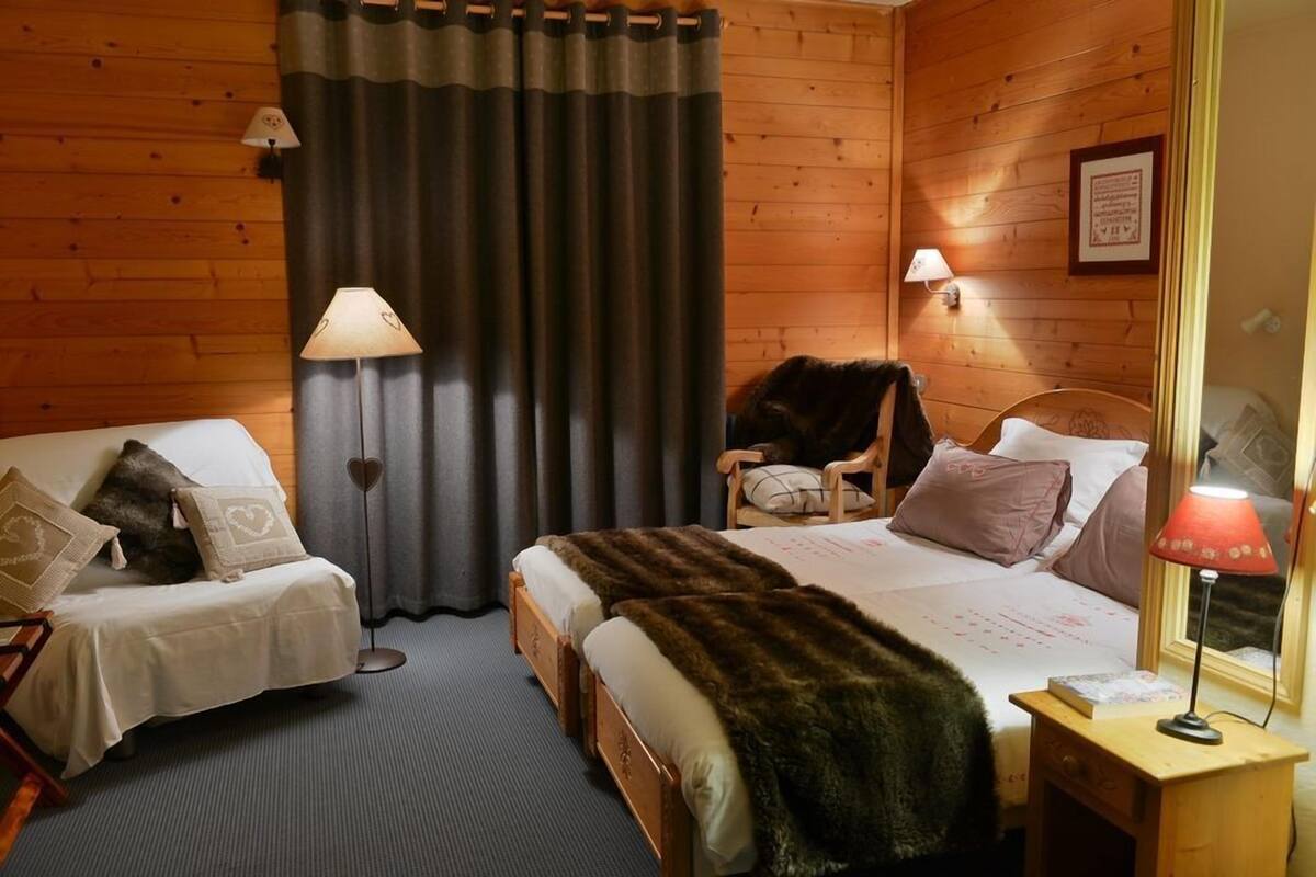 A cozy room with two beds, a chair, and a desk.