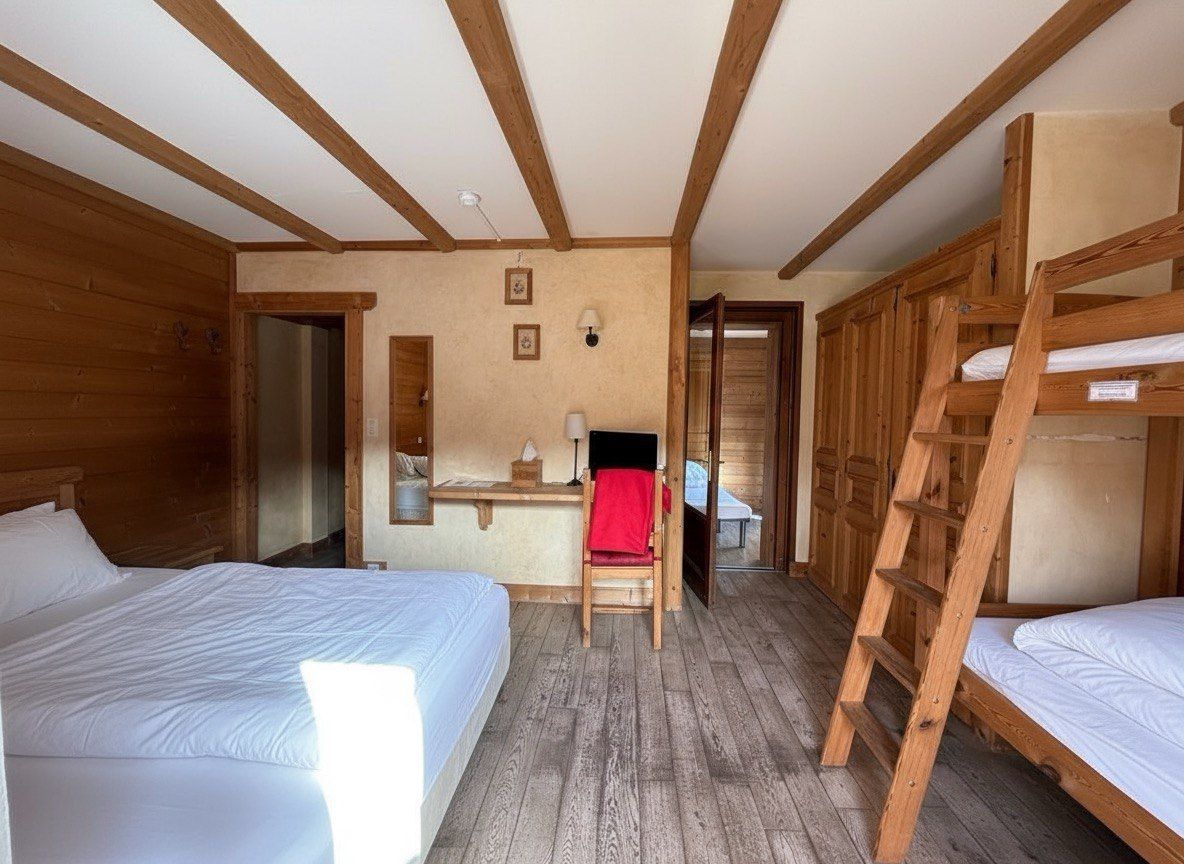 Una habitación con dos camas, un escritorio y una escalera.