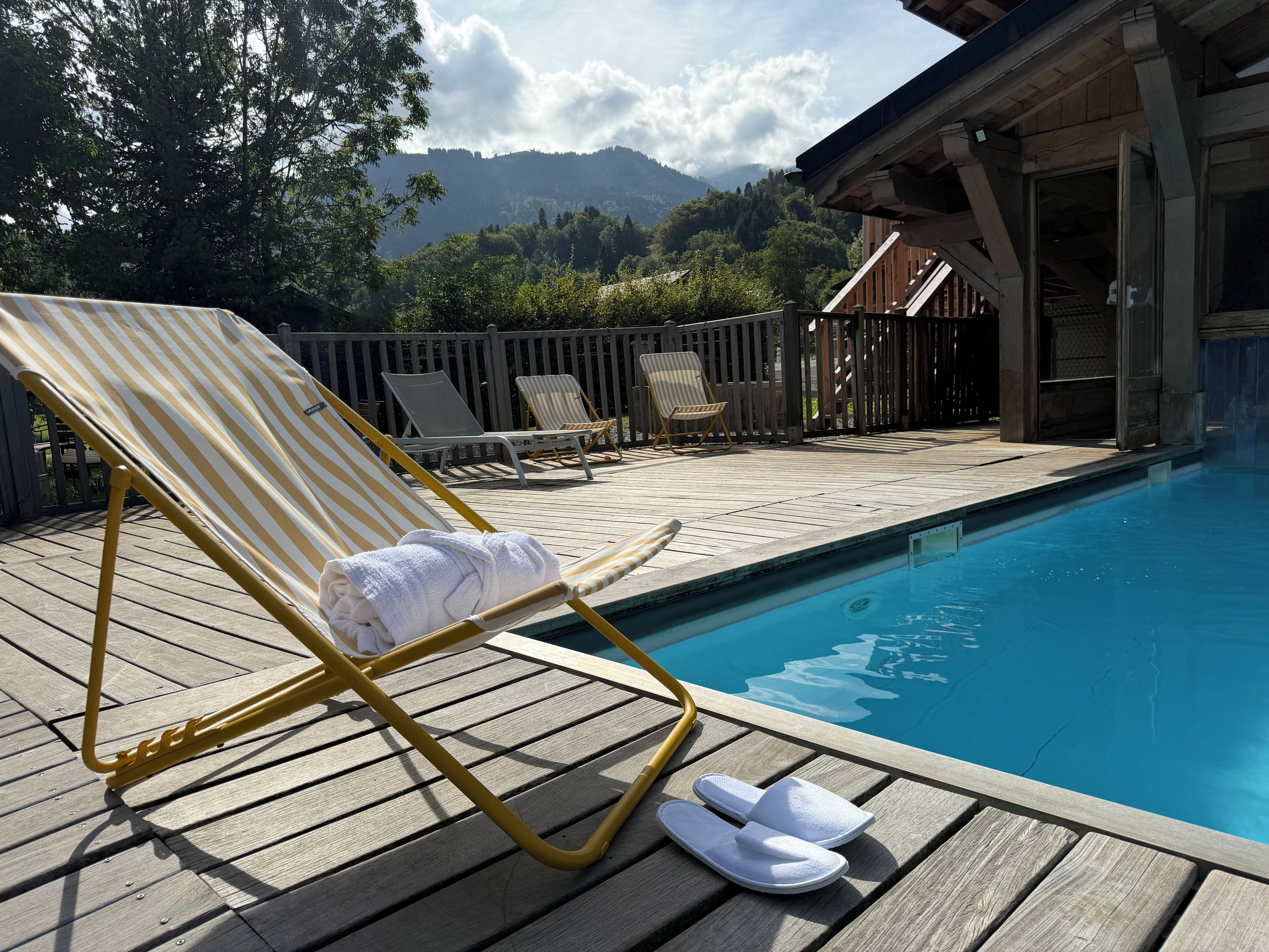 A poolside area with lounge chairs and a pair of slippers.