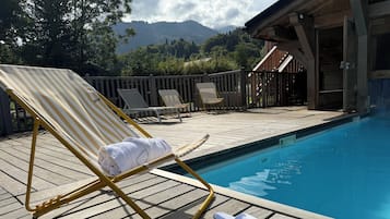 A poolside area with lounge chairs and a pair of slippers.