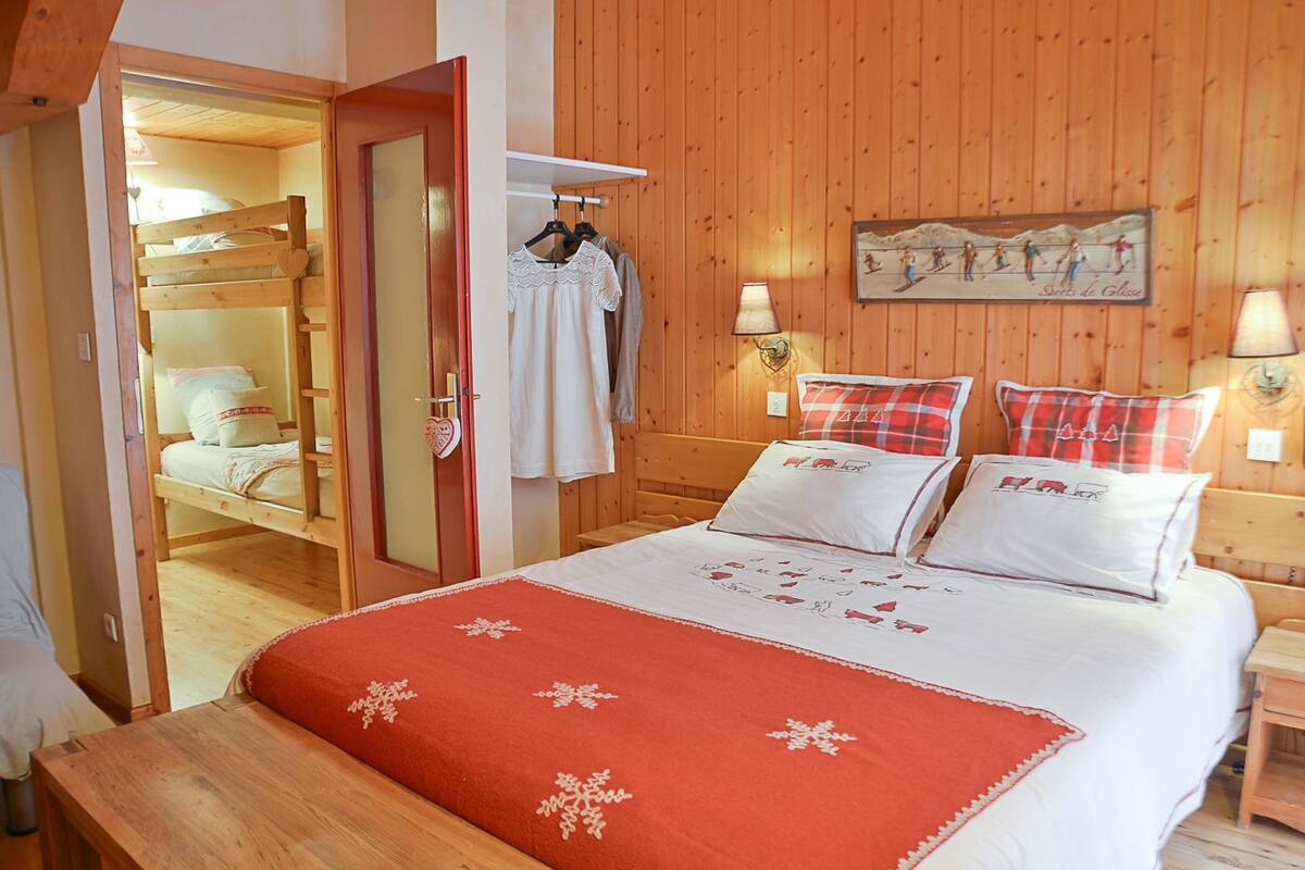 A wooden-paneled room with a bed, a bench, and a wardrobe.