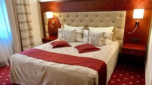 Une chambre d’hôtel avec un grand lit, deux tables de chevet et une tête de lit dotée d’un éclairage intégré.