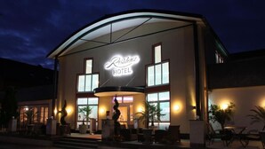 Un hôtel avec une enseigne bien visible, une entrée abritée et des places assises à l’extérieur.