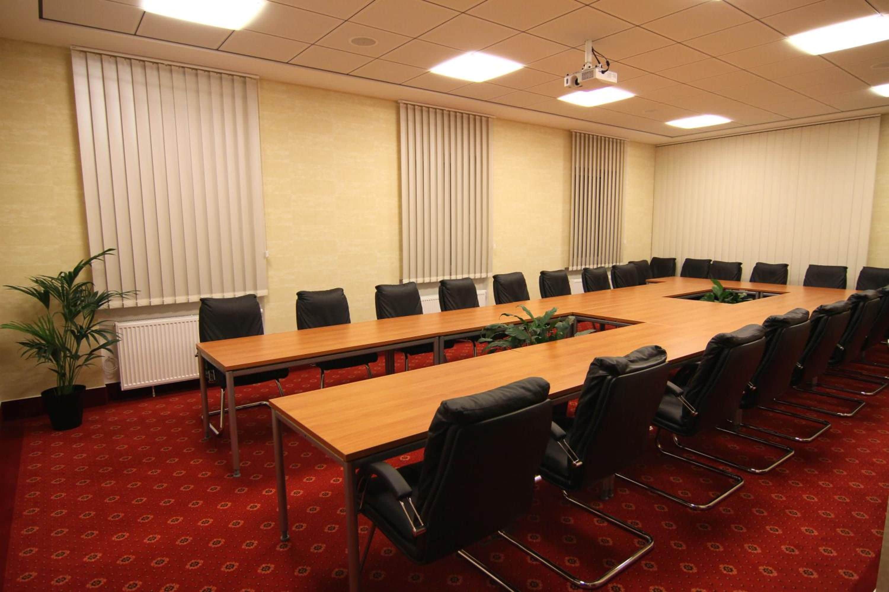 A conference room with a long table, black chairs, and a projector.