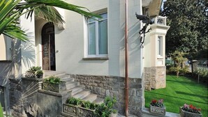 A house with a stone staircase, a door, and a bird sculpture. - VIlla Maurice (Stresa)