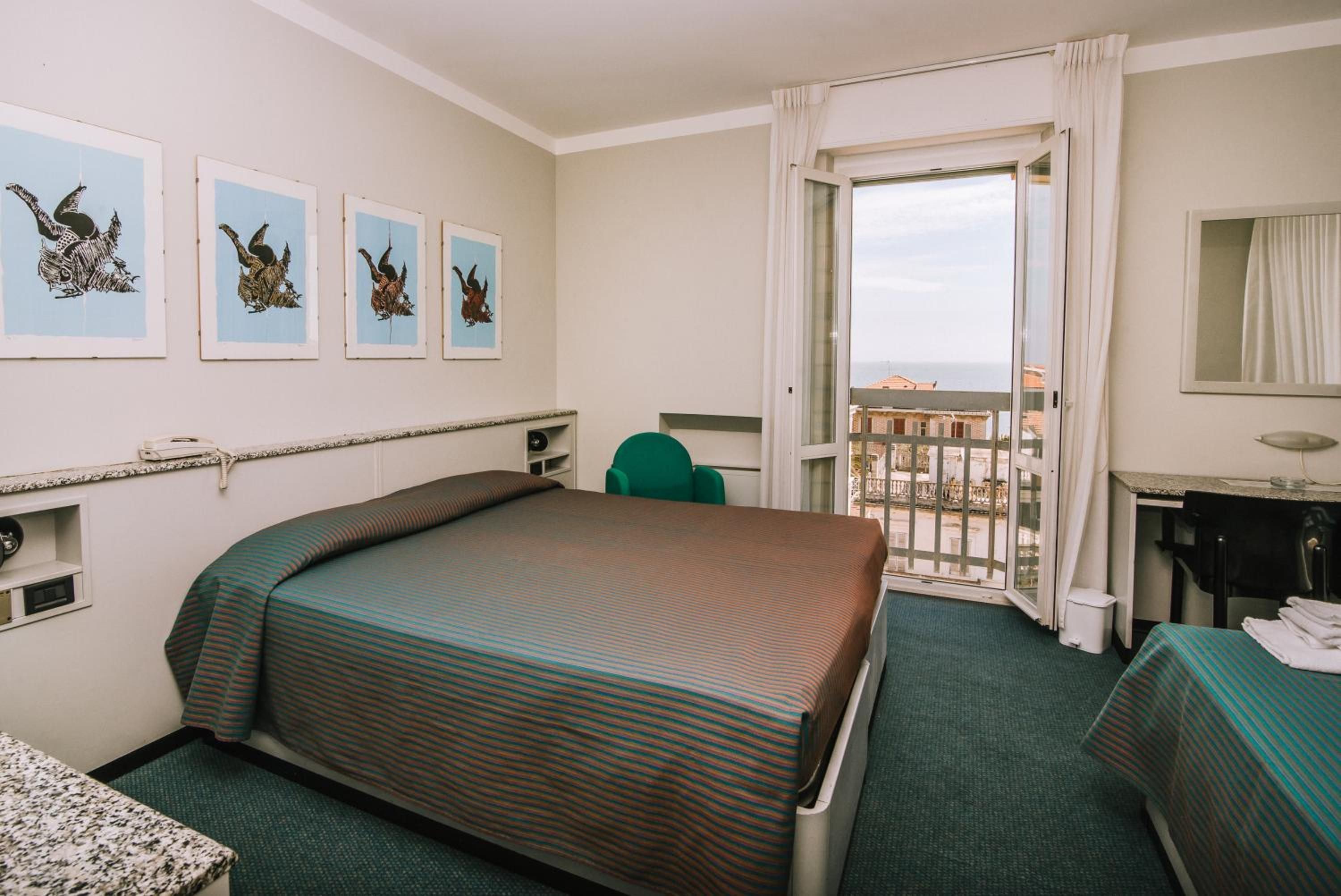 Una camera d'albergo con un letto, una scrivania, una sedia e un balcone con vista.