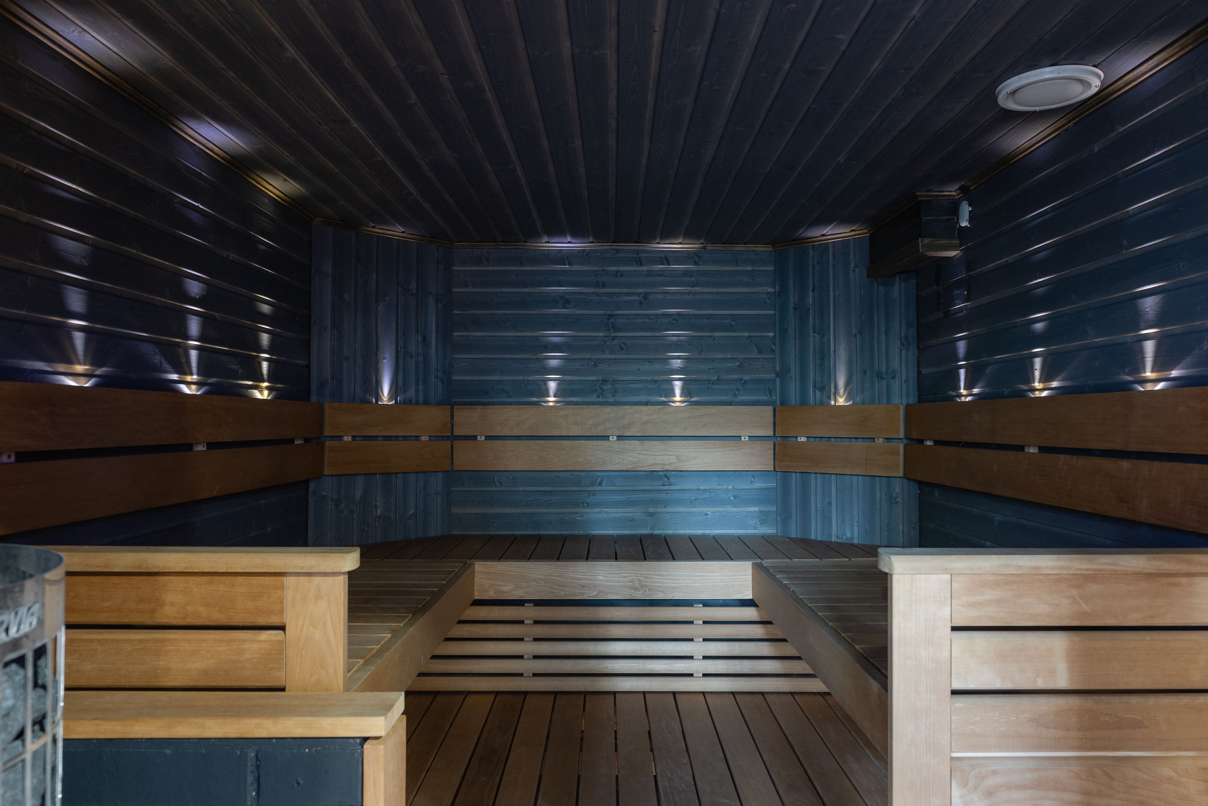 A sauna with wooden benches and a sloped floor leading to a central area.