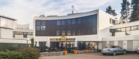 A modern building with a reception area, outdoor seating, and a parking area.