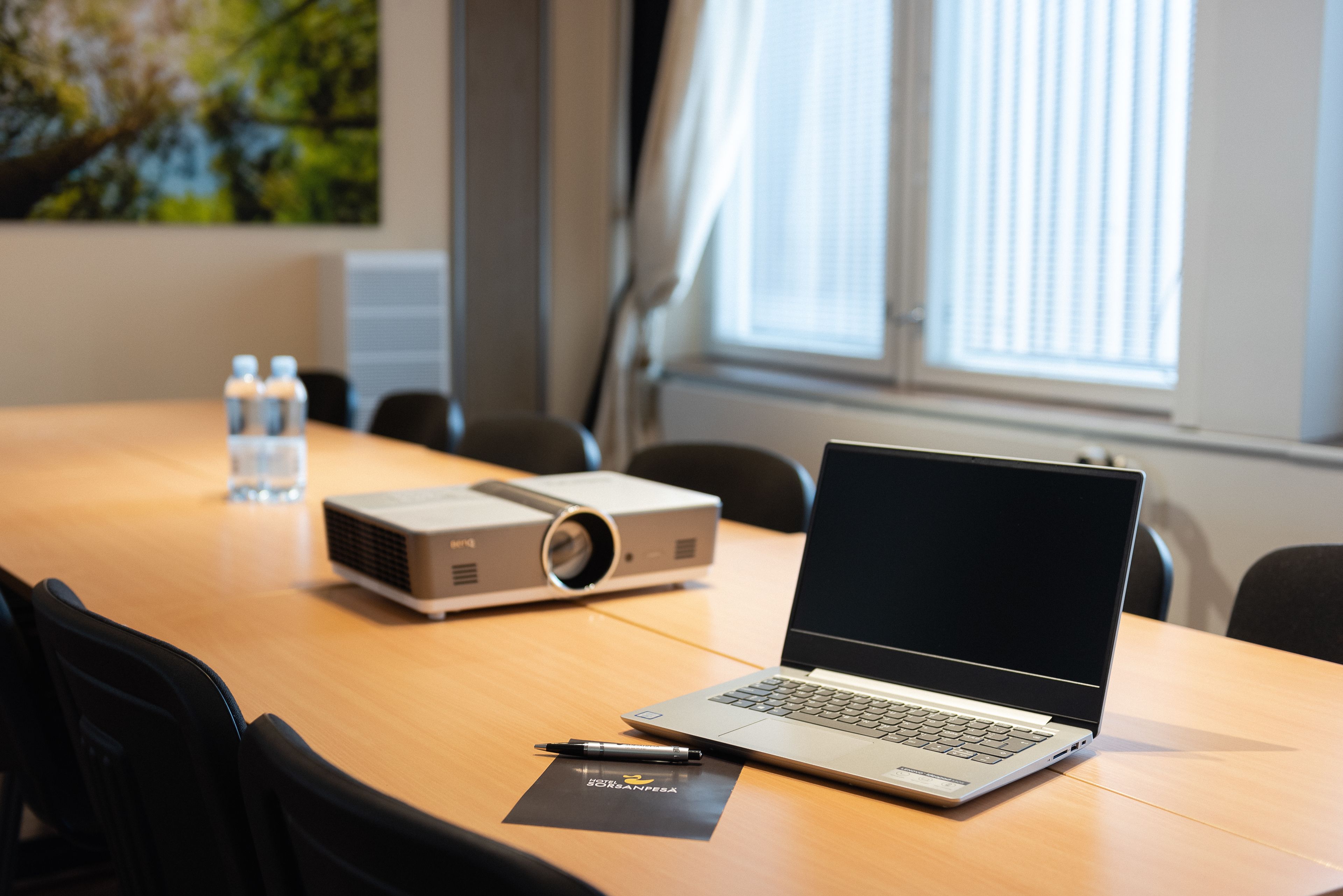 A conference room with a laptop, projector, and water bottles on a table.