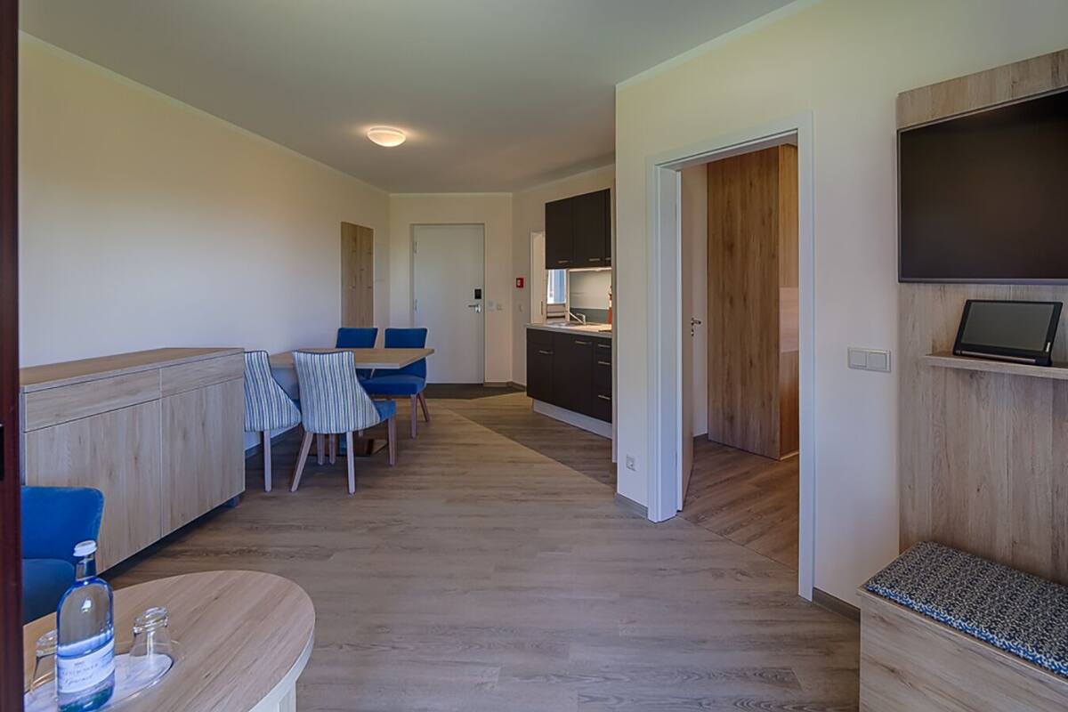 A modern kitchen with dark cabinets, a dining area with blue chairs, and a wooden bench.