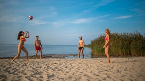 Escena de playa con cuatro personas jugando voleibol.