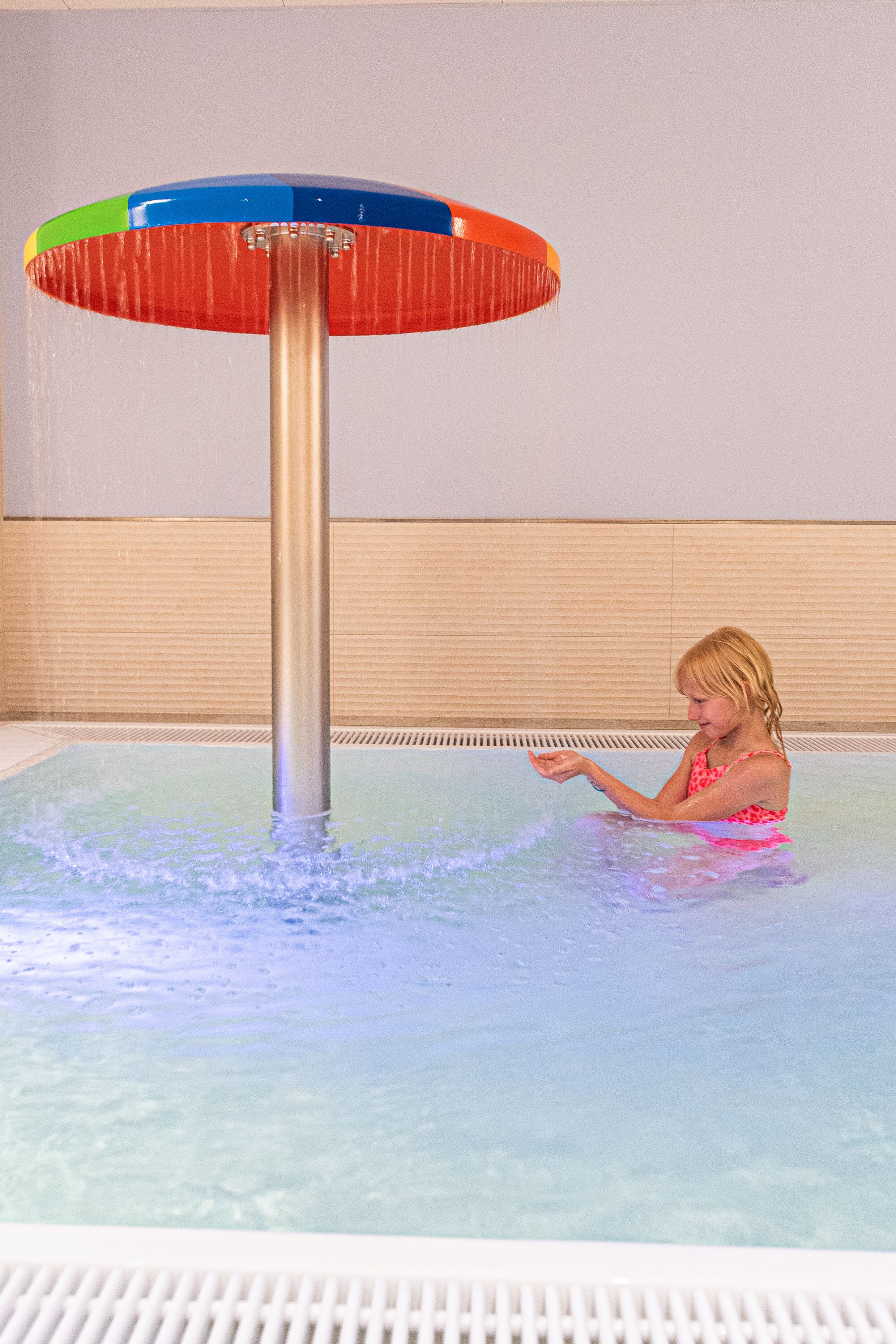 A person in a pool with a water feature.