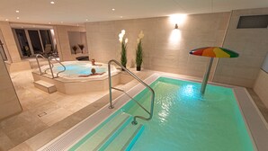 Una piscina con hidromasaje, una escalera y un paraguas colorido.