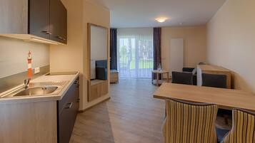 A modern kitchen with a sink, a dining area with a table and chairs, and a view of a balcony with curtains.