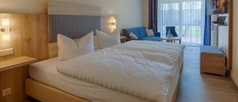 A modern hotel room with a large bed, a desk, a chair, and a TV.