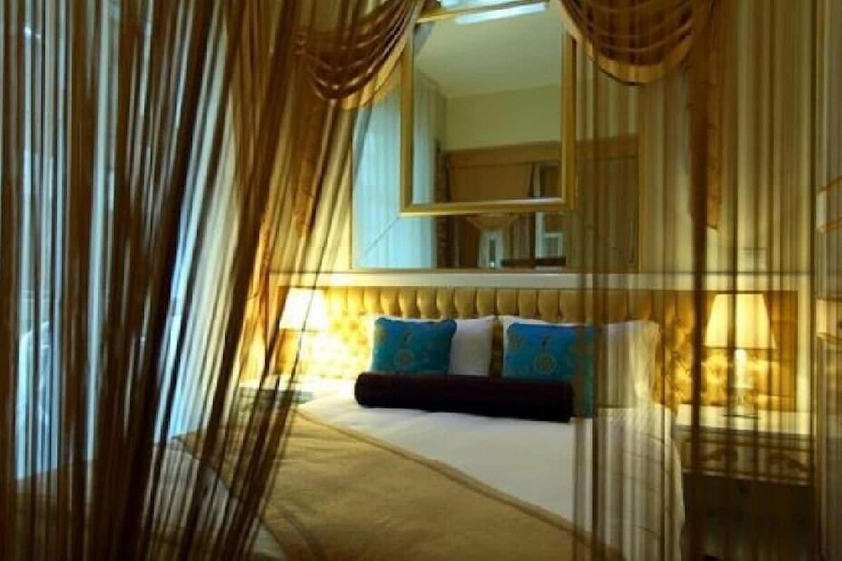 A hotel room with a bed, curtains, and a mirror.