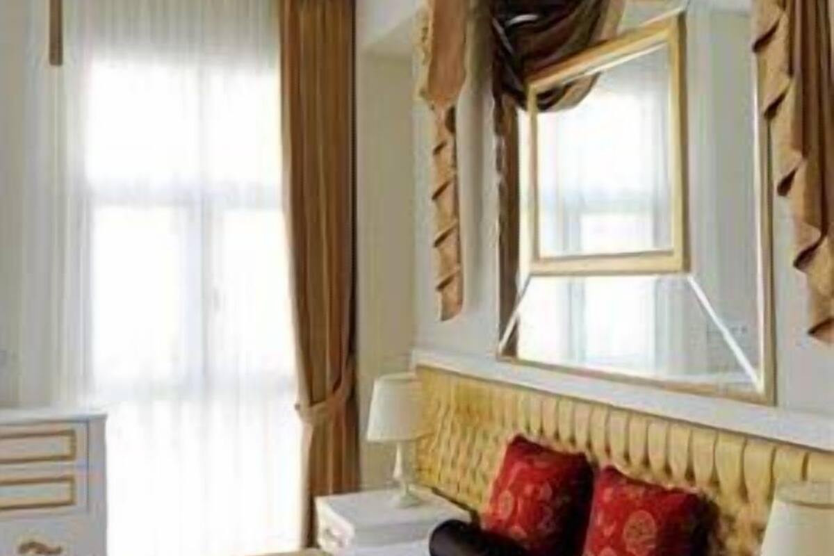 A hotel room with a bed, bedside tables, a dresser, and curtains.