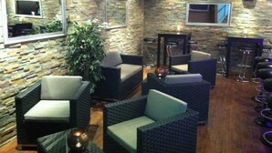 A lounge area with stone walls, cushioned seating, and bar stools. - SEELANDHOTEL Weisses Kreuz (Lyss)