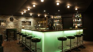A bar area with a green-lit bar counter, multiple stools, and a well-stocked liquor shelf. - SEELANDHOTEL Weisses Kreuz (Lyss)