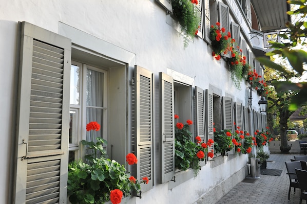 A row of windows with shutters, some open, and red flowers in the window boxes. - SEELANDHOTEL Weisses Kreuz (Lyss)