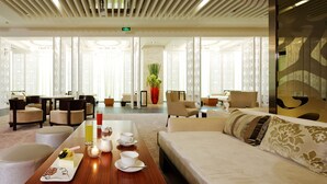 Un vestíbulo de hotel con mostrador de recepción, zona de estar y una mesa de comedor con postre y bebidas.