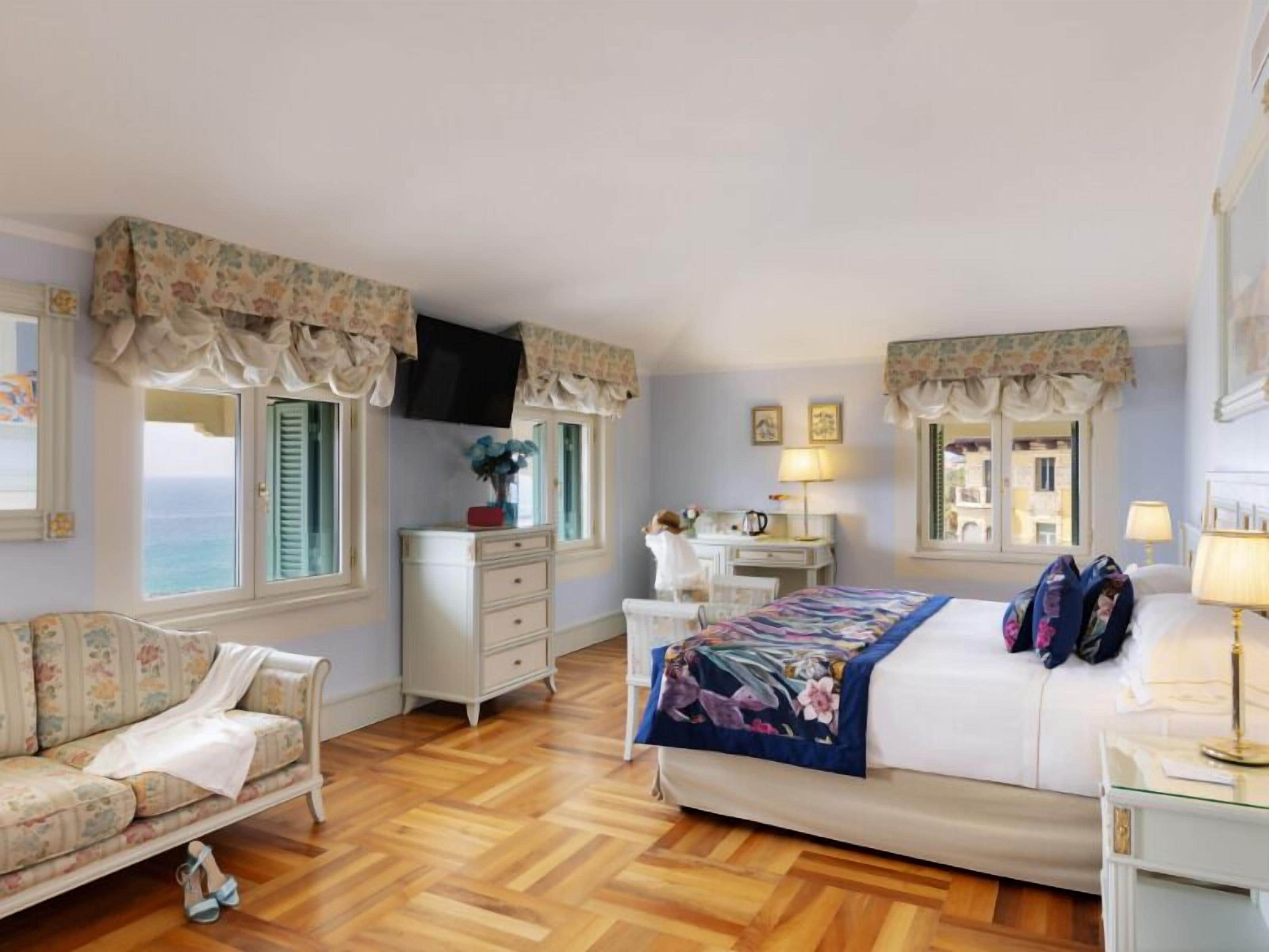 A bedroom with a bed, a desk, a chair, a dresser, and a television.
