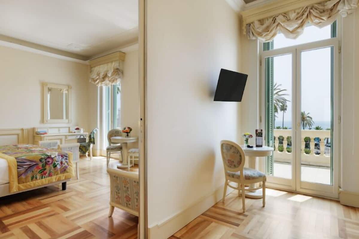 Ein Hotelzimmer mit Bett, Schreibtisch, Stuhl, Fernseher und einem Balkon mit Blick.
