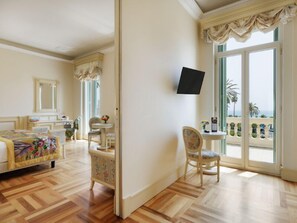 A hotel room with a bed, a desk, a chair, a television, and a balcony with a view.