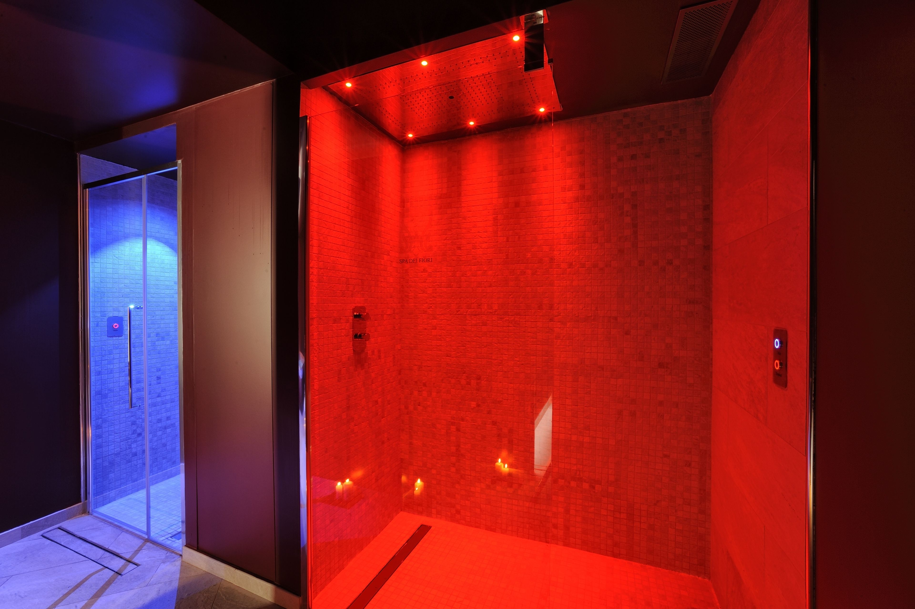 A red-lit elevator with a tiled wall and a glass door.