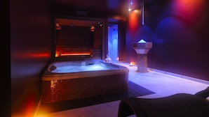 Un espace bien-être comprenant un jacuzzi, un fauteuil de massage et une fontaine décorative.