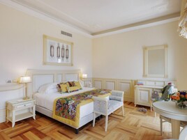 Un dormitorio con cama, mesitas de noche, una silla, una mesa con flores y un espejo.