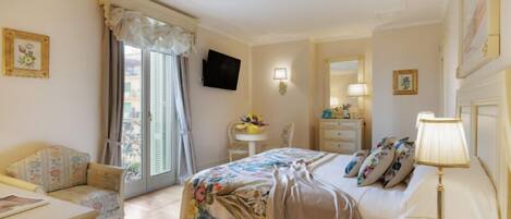 A hotel room with a bed, a desk, a chair, a TV, a lamp, and a window with curtains.