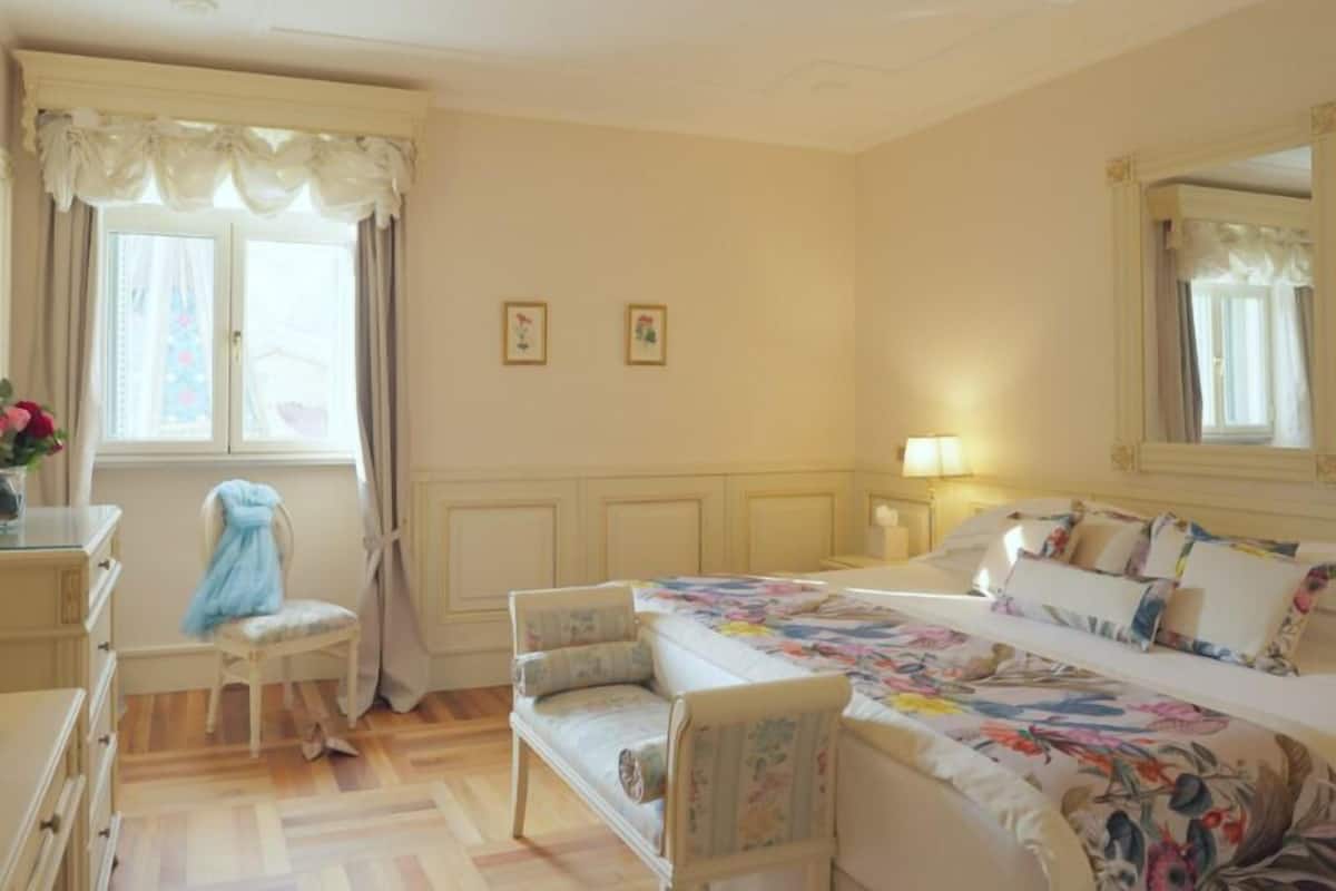 Ein Hotelzimmer mit Bett, Stuhl, Schreibtisch und einem Fenster mit Vorhängen.
