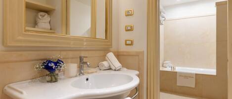 A bathroom with a large mirror, a sink, a towel rack, and a shower area.