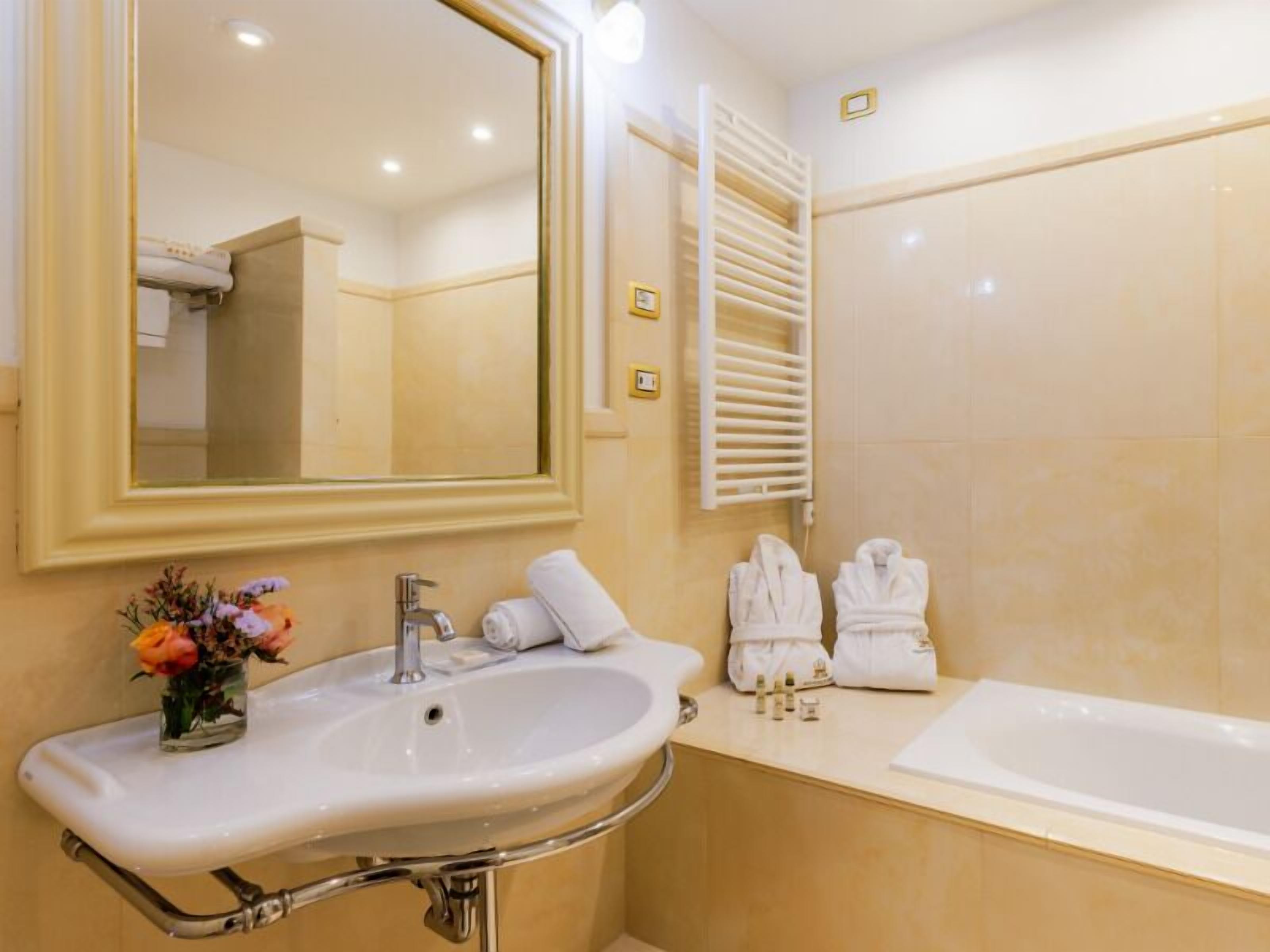 Ein Badezimmer mit Waschbecken, Spiegel, Handtuchhalter und Badewanne.