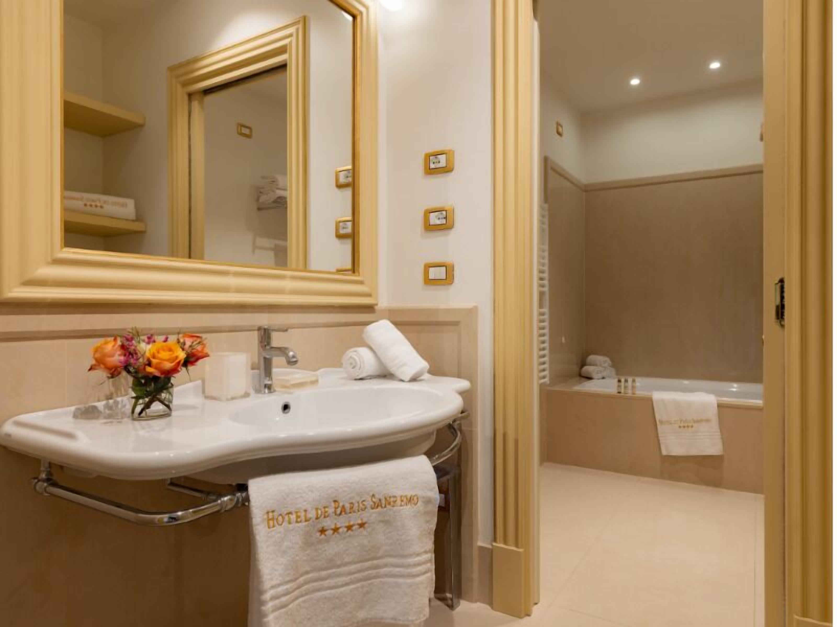 A bathroom with a large mirror, a sink, a towel rack, and a shower area.