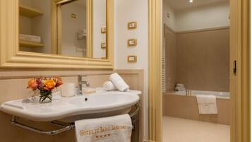 A bathroom with a large mirror, a sink, a towel rack, and a shower area.