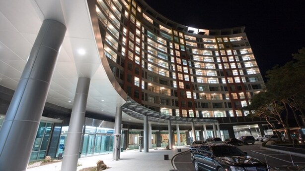 A modern hotel with a curved facade, large windows, and a covered entrance area. - Mayhills Resort (Jeongseon)
