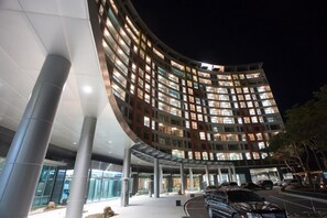 Un hotel moderno con fachada curva, ventanas amplias y zona de acceso cubierta.