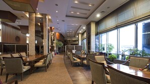 A spacious hotel lobby with a long reception desk, multiple seating areas, and large windows offering a view of the city. - Mayhills Resort (Jeongseon)