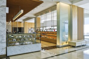 A modern interior with a glass display case of pastries, a seating area, and a reception desk.