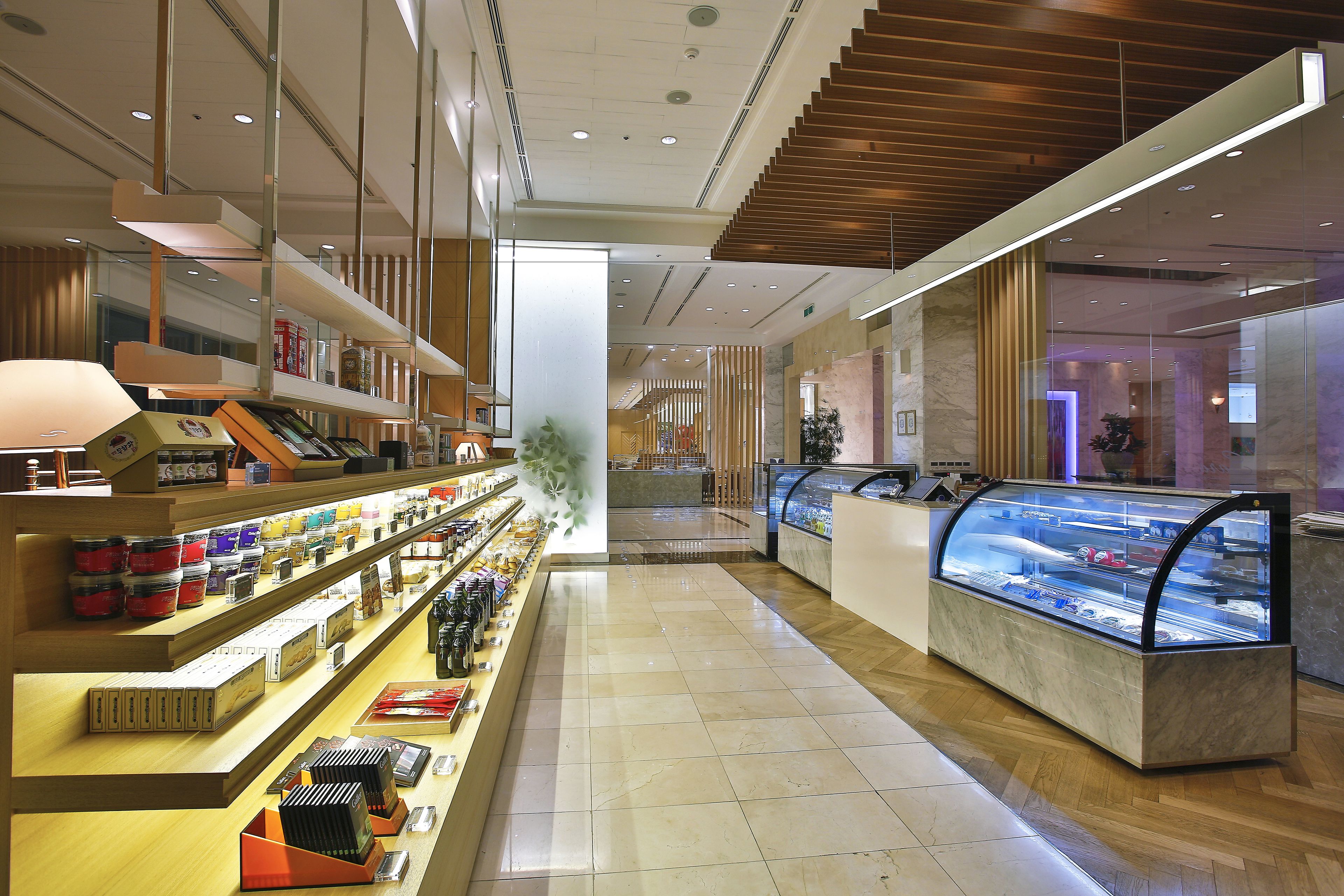 A modern hotel lobby with a marble floor, a reception desk, and a glass display case.