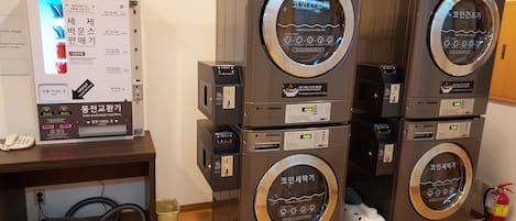 A stack of coin exchange machines with a digital display and a small screen, placed next to a whiteboard with instructions.