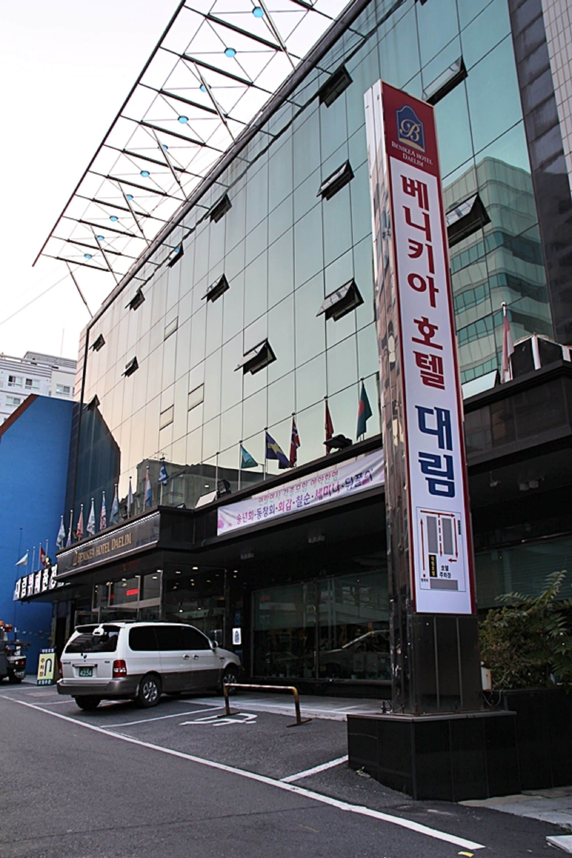 Ein modernes Gebäude mit einer großen Glasfassade und einer auffälligen vertikalen Beschilderung mit koreanischen Schriftzeichen.