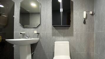 Une salle de bain avec un lavabo blanc, des toilettes, un miroir et un meuble de rangement.