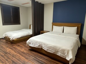 A hotel room with two beds, wooden flooring, a window with blinds, and a blue accent wall. - Benikea Hotel Daelim (Daejeon)