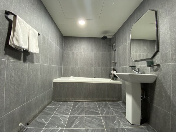 Un baño moderno con bañera, lavabo y espejo.