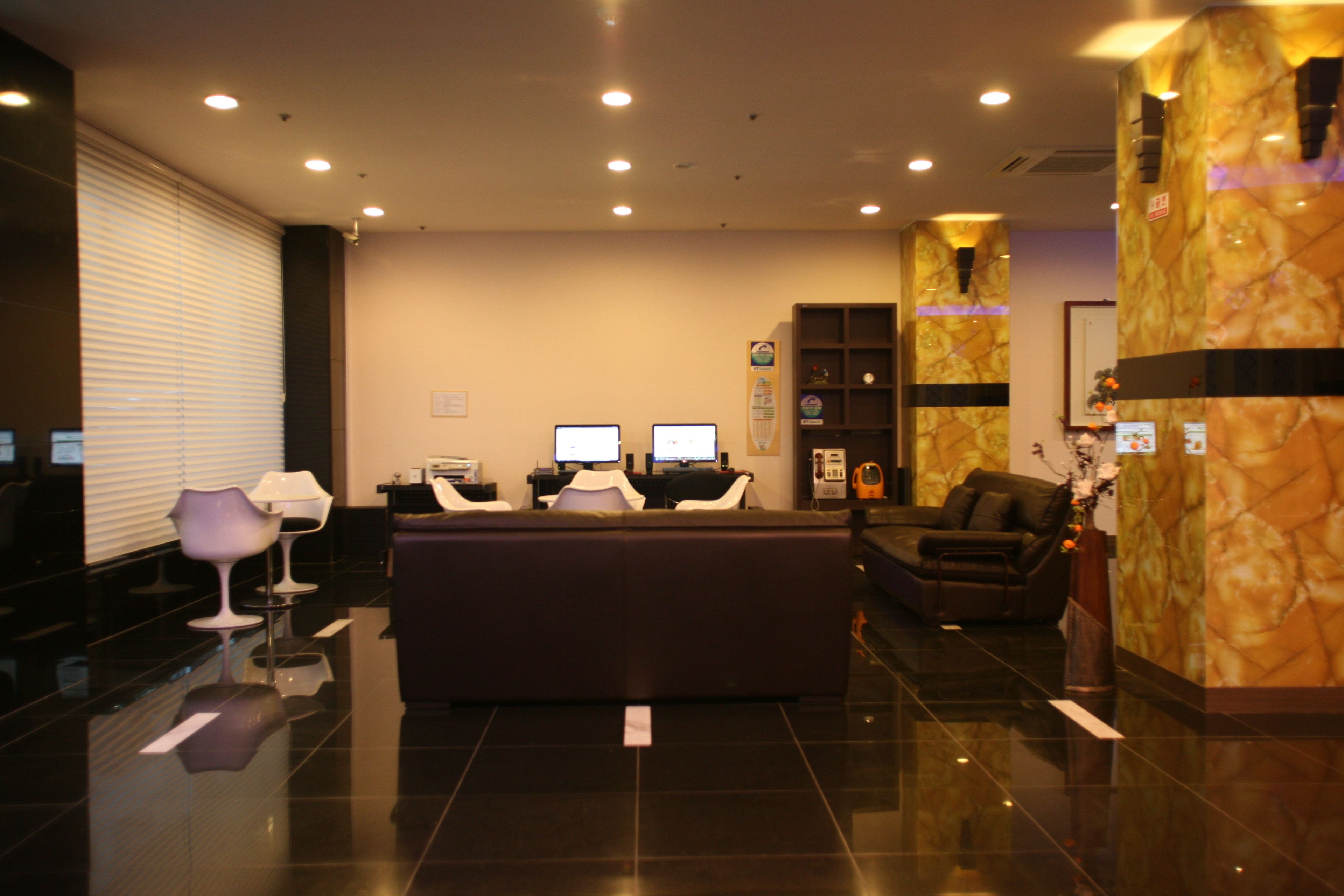 A reception area with a dark-colored sofa, two computer monitors, and a reception desk.
