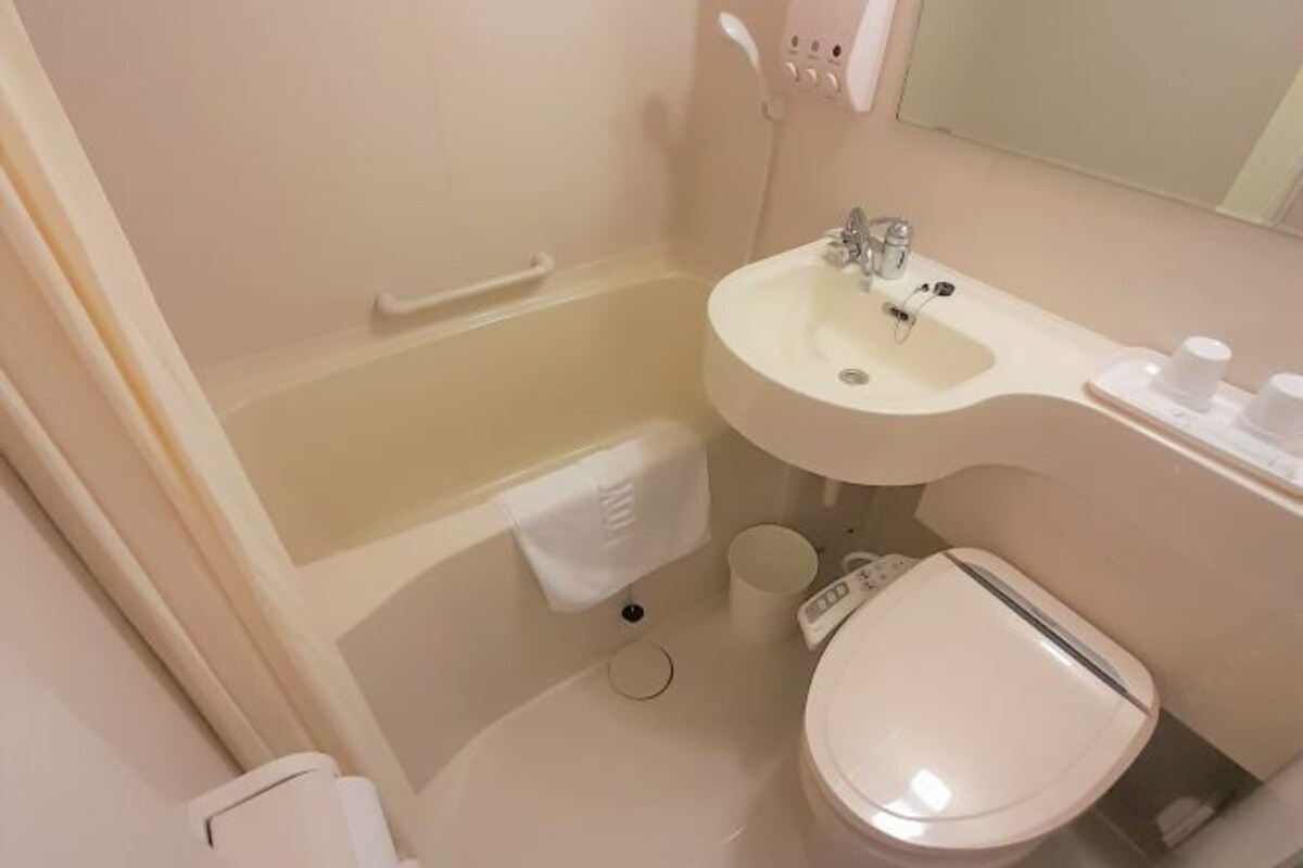 A bathroom with a bathtub, sink, toilet, and a mirror.
