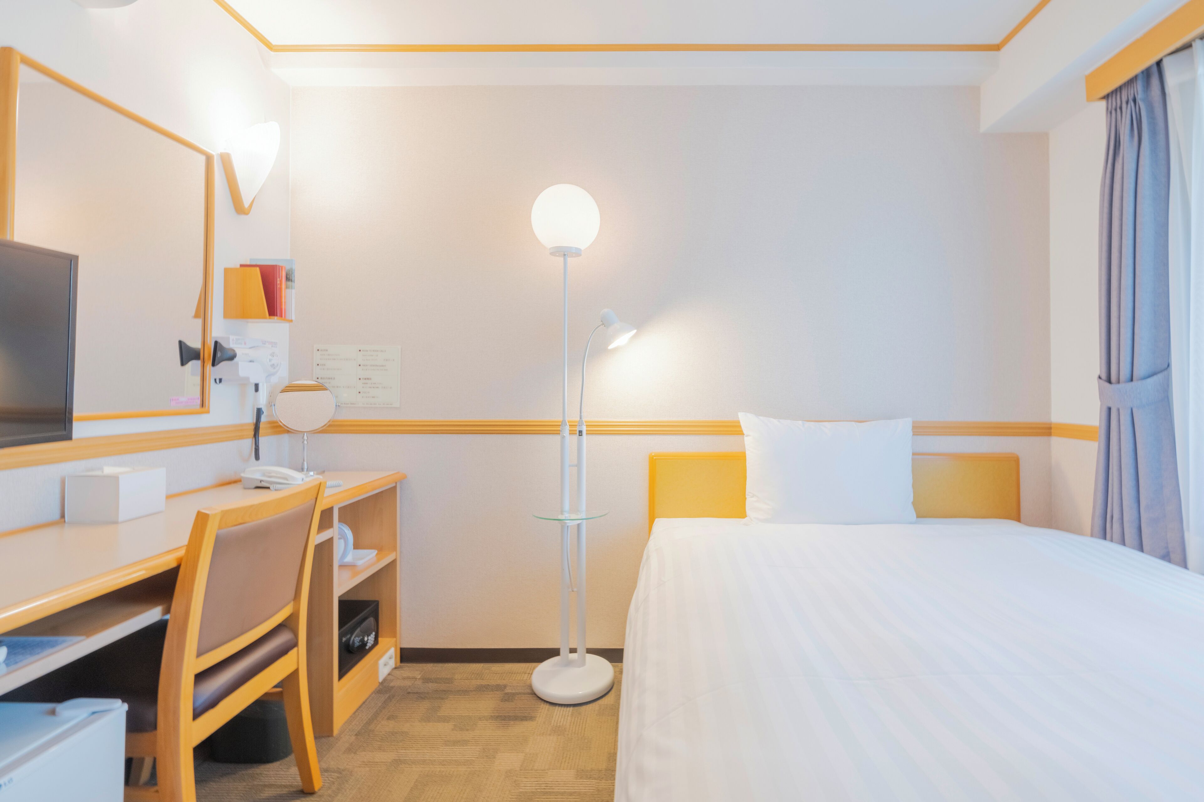 Ein Hotelzimmer mit Bett, Schreibtisch, Stuhl und Stehlampe.